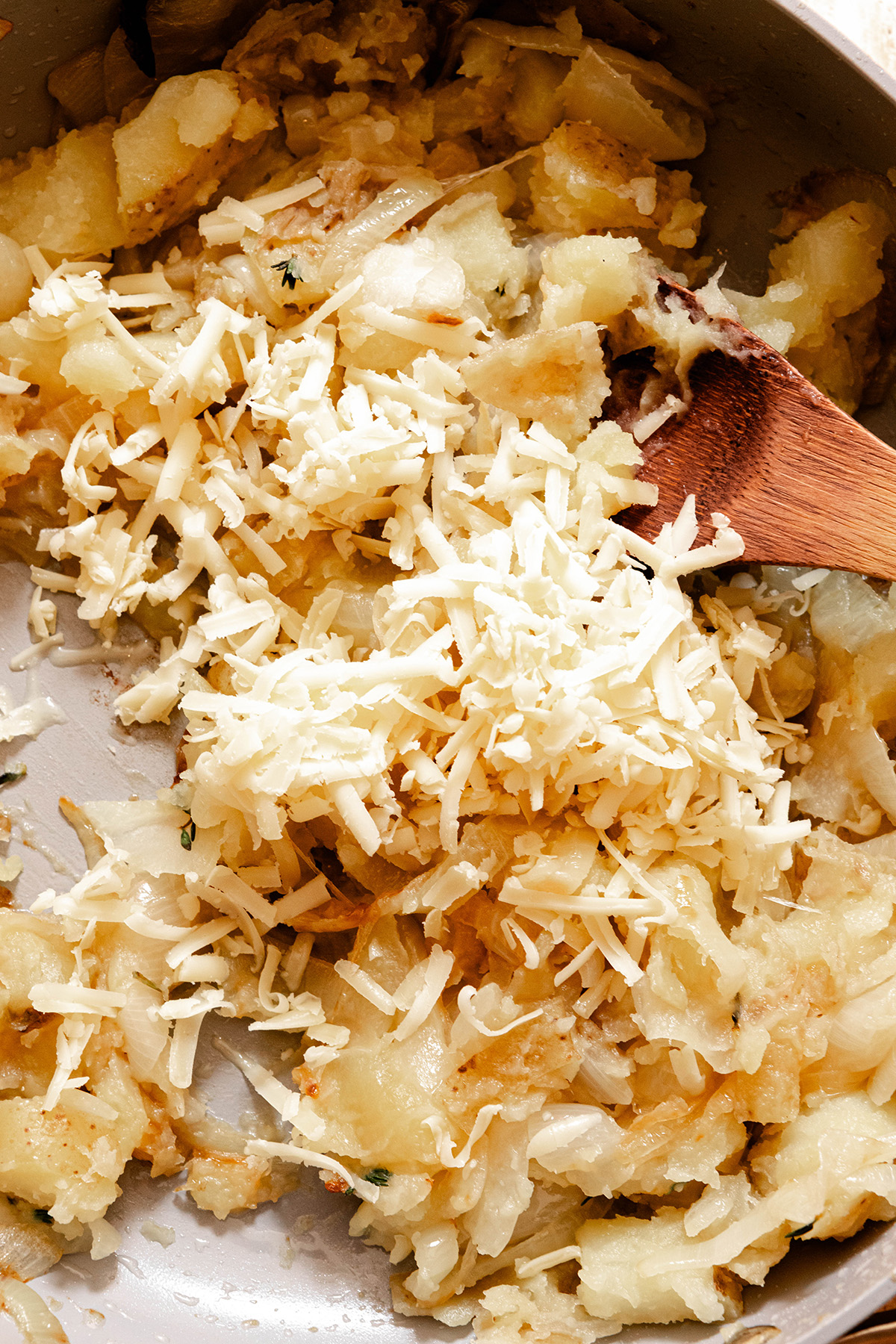 potatoes onions spices and cheese in a pan