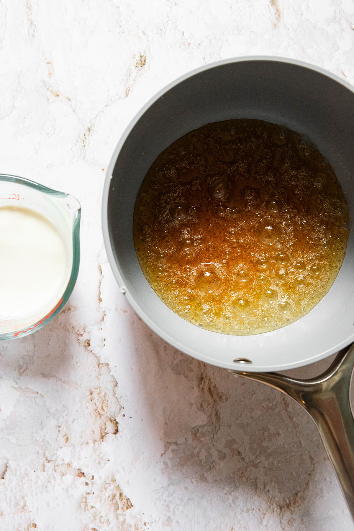 boiled sugar in a pot with cream in a measuring cup