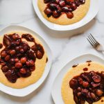 3 white plates with golden polenta topped with vegetarian bourguignon.