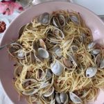 Linguine and clams with red pepper flakes sitting in a pink serving bowl.