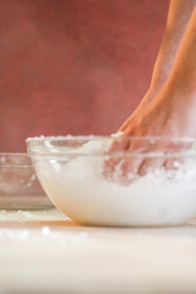 fondant being mixed together in a glass bowl by hand