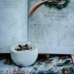 Polyjuice potion in a clear glass sitting in front of a book.
