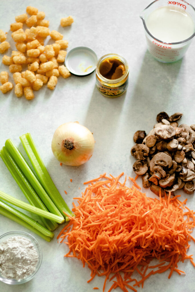 ingredients for a vegetable tater tot casserole on a white surface