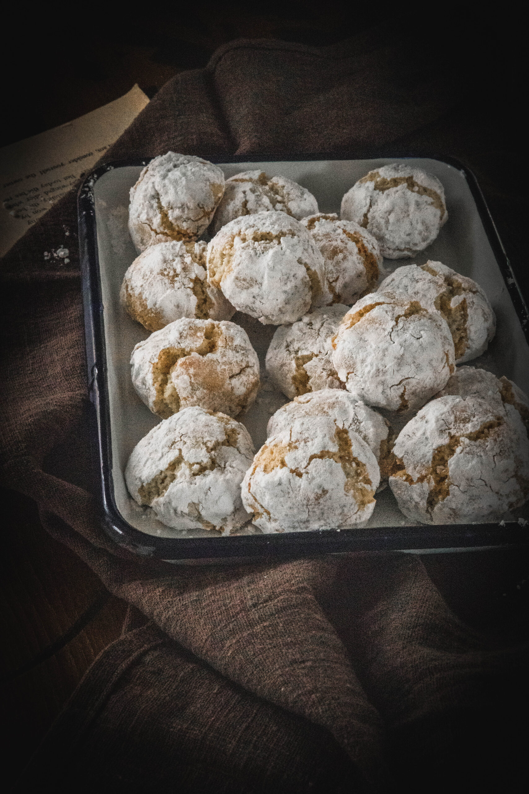 Soft amaretti cookies in a white container on a brown cloth