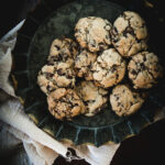 Gluten Free Chocolate Heath Bar Cookies in a green plate on a beige cloth on a wooden background